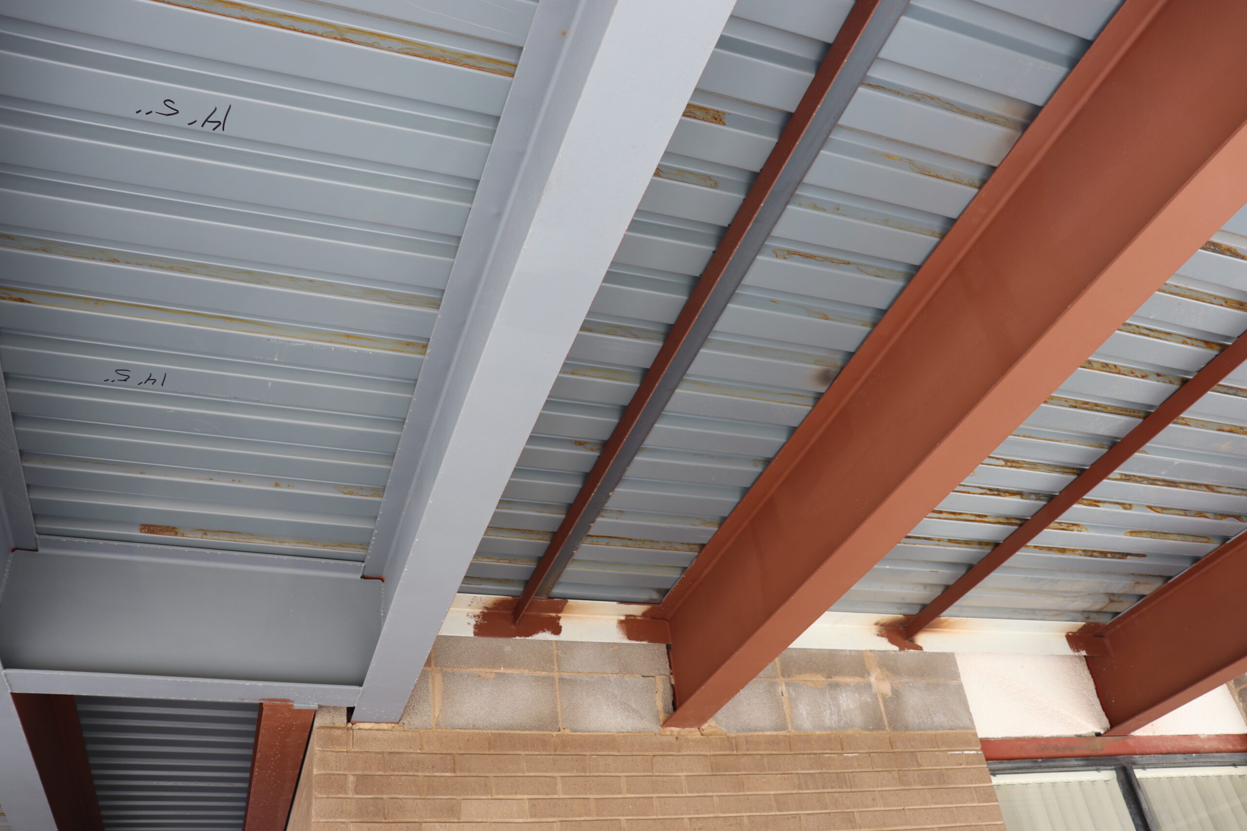 Unlike the original 1970 balcony, the 2021 replacement includes more overall support features, such as additional I-beams (left) and a layer of corrugated steel under the concrete walkway. [Photo by Lance Ziesch]