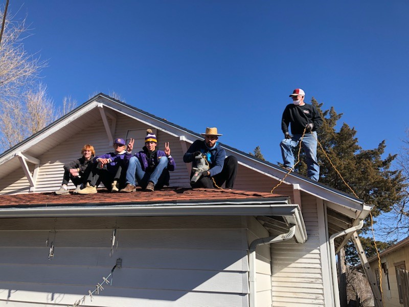 DC3 Baseball team and volunteers cleaning gutters from a rooftop during the RSVP Annual Clean-Up Day